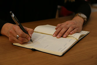 Frau schreibt mit Stift auf Papier